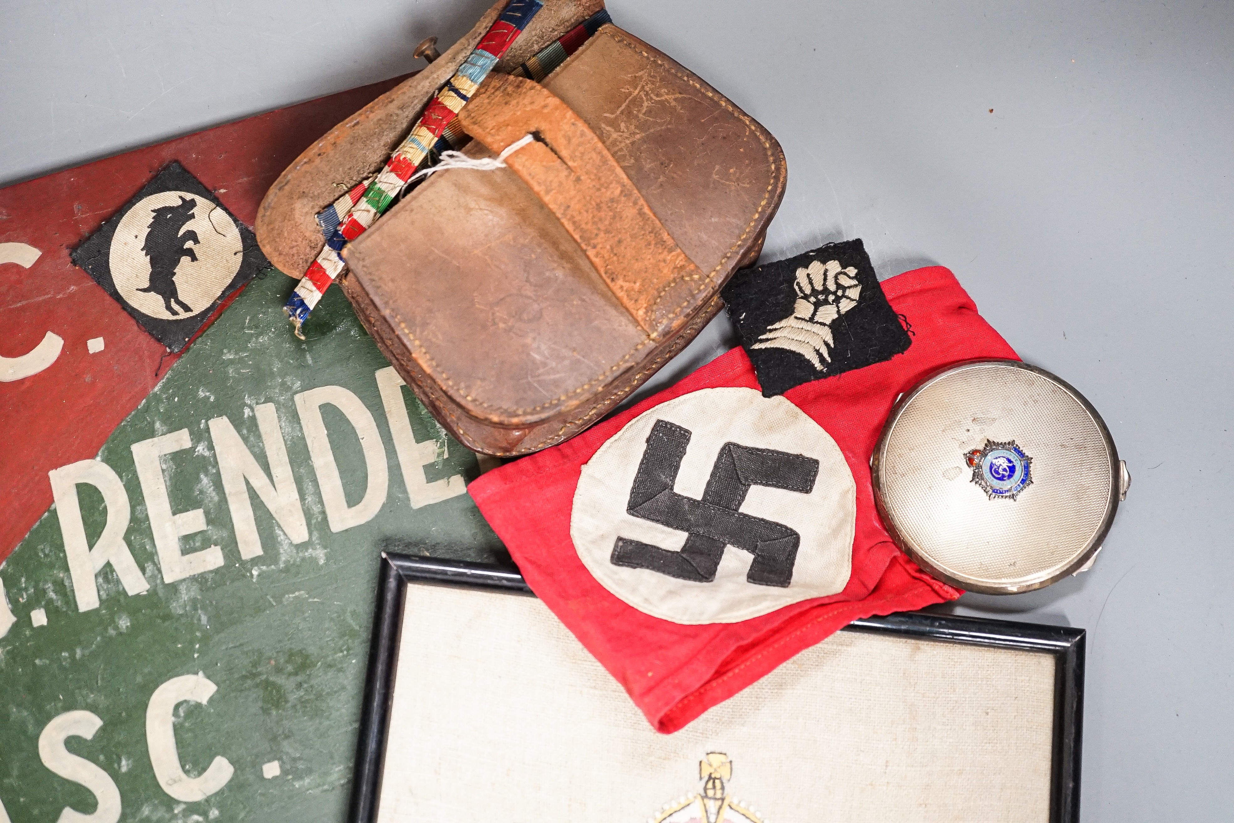 A group of WWI and WWII militaria badges, buttons, two swagger sticks, an armband and a World War I German POW inscribed plaster ornament, longest swagger stick 70 cms long.